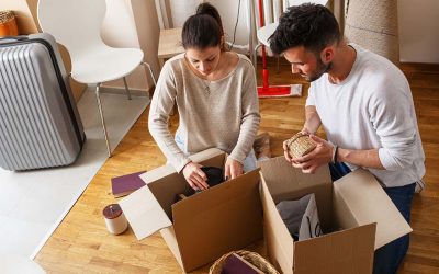 Young Couple Unpacking Cardboard Boxes At New Home.