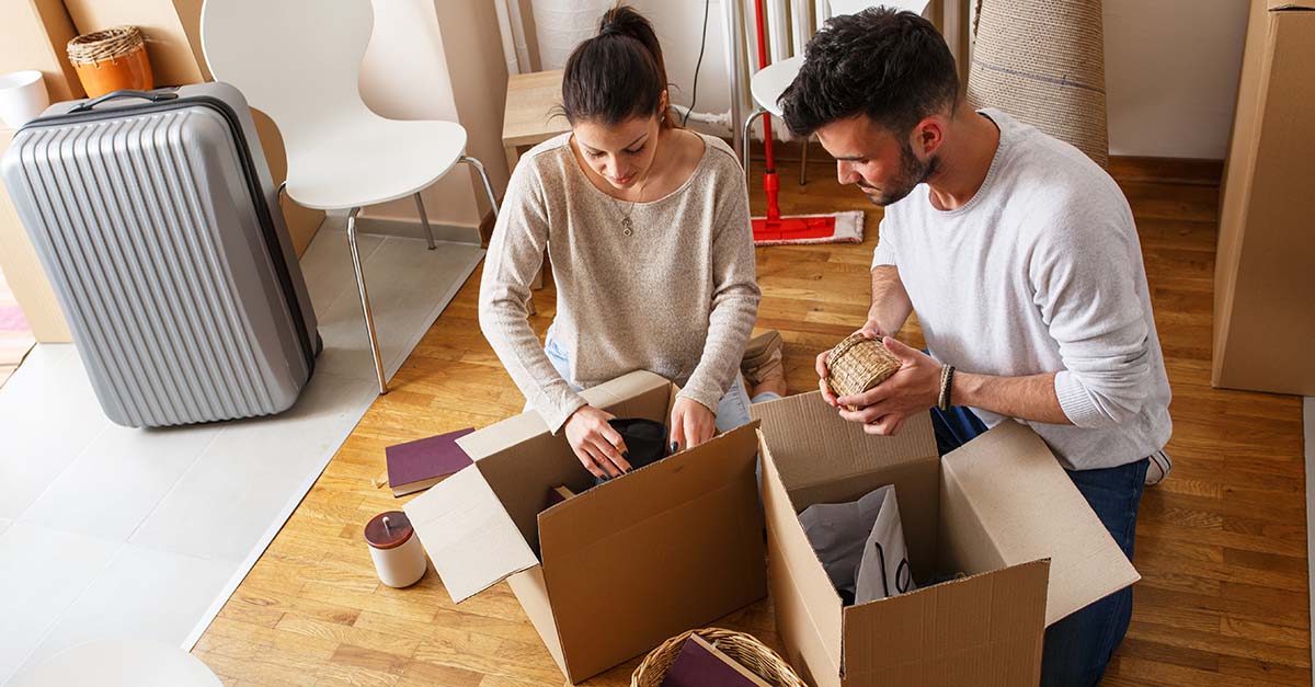 Young Couple Unpacking Cardboard Boxes At New Home.